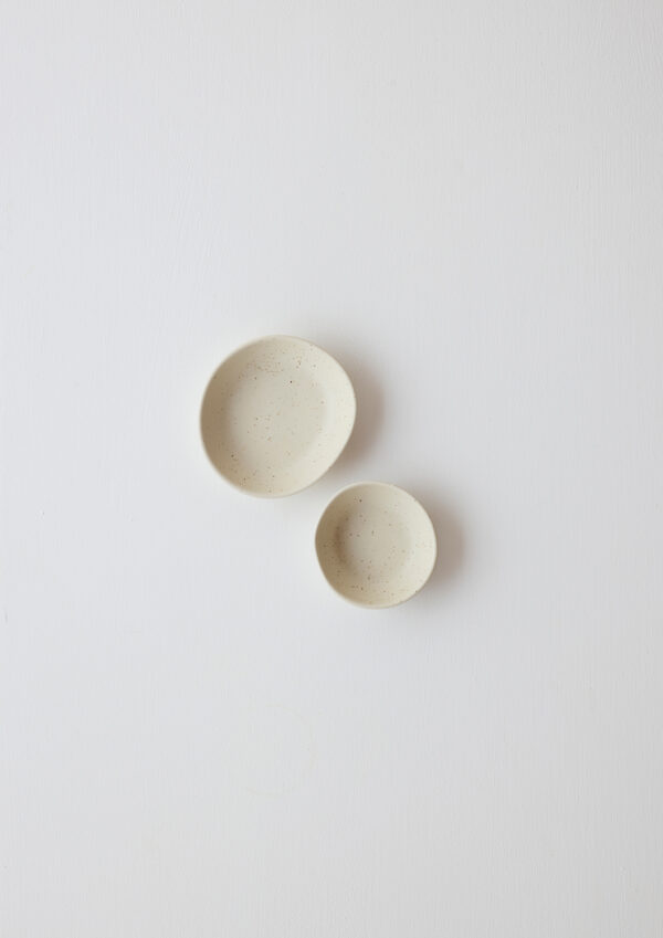 Pair of pale pistachio high-fired porcelain dipping bowls in oatmeal with sculptural curves and speckled glaze.