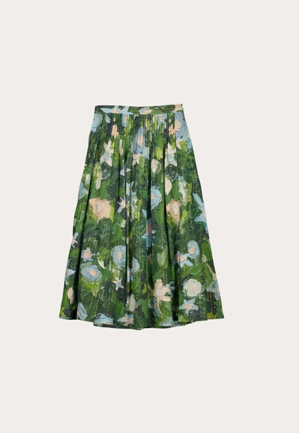 Nancybird Alma Yoke Skirt in Garden print displayed on model among flowers—lightweight cotton voile fabric, green and gold botanical pattern, midi silhouette