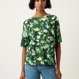 Model wearing Nancybird Grace Tee in Garden print—relaxed organic cotton crew‑neck tee featuring Emily Wright botanical artwork on light blue background