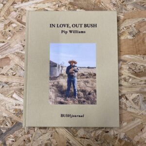 The cover of In Love Out Bush features a striking photograph of a rural Australian landscape, symbolizing the deep connection between people and the land. The cloth-bound hardcover adds a tactile quality, reflecting the book's intimate and heartfelt content.