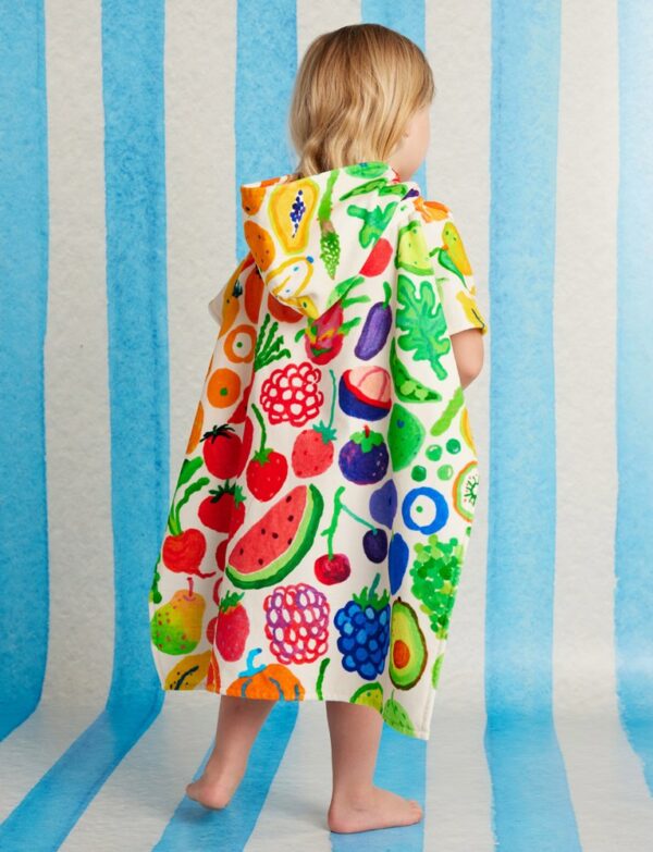 Model wears Halcyon Nights Kids Hooded Towel in Eat The Rainbow print—colourful poncho-style towel with hood, soft cotton fabric and Seeun Park artwork
