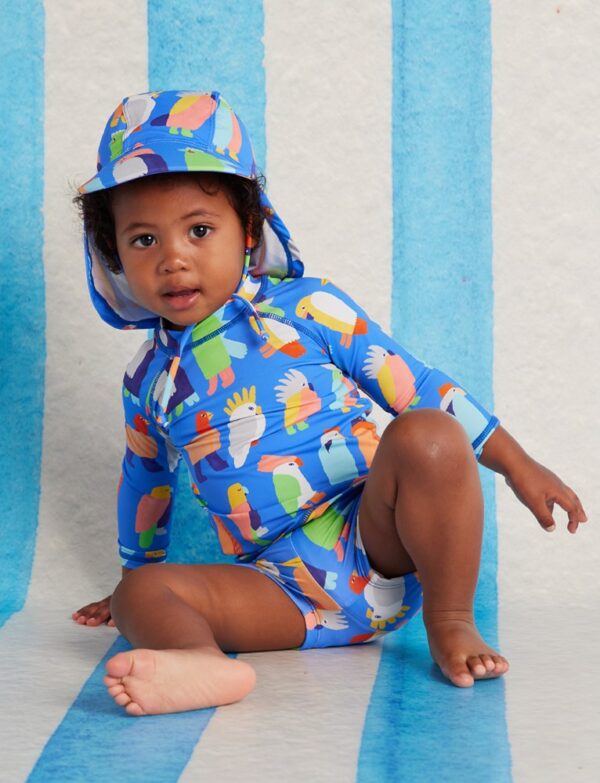 Model wears Halcyon Nights Long Sleeve Rash Vest in Flamin' Galahs print—baby swim top with pink galahs, full-length sleeves, and UPF 50+ recycled fabric