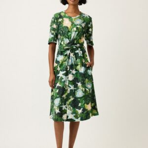 Model wears Nancybird Terra Short Sleeve Wrap Dress in Garden print—organic cotton jersey midi dress with short sleeves, crew neck, wrap tie waist and botanical green‑leaf artwork