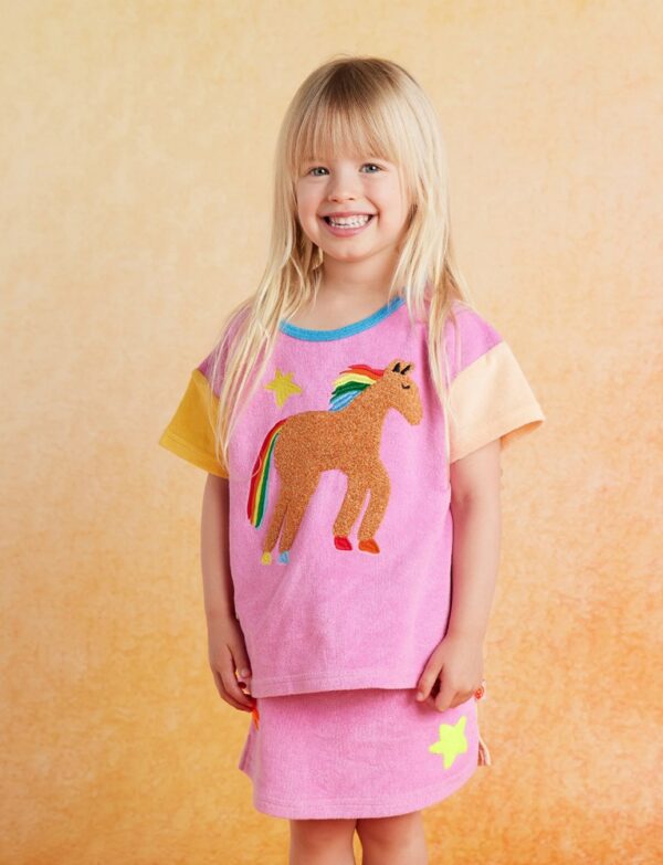 model wears Halcyon Nights Giddy Up Terry Skirt—kids’ cotton skirt with elastic waistband and boucle horse applique, perfect for layering in winter