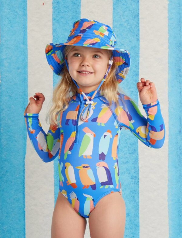 Model wears Halcyon Nights Long Sleeve Zip Bather in Flamin' Galahs print—kids swimwear with full sleeves, front zip, pink galah artwork, and UPF 50+ recycled fabric