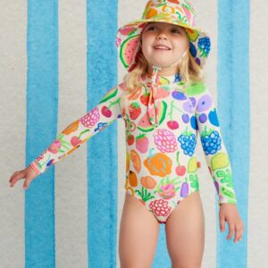 model wears Halcyon Nights Long Sleeve Zip Bather in Eat The Rainbow print—kids swimsuit with front zip, full sleeves, bright rainbow design, and UPF 50+ protection